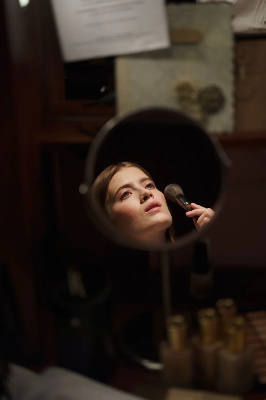 Artista frente a un espejo con una brocha de maquillaje